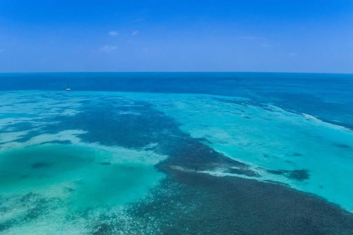 Wide aerial of turquoise Caribbean shallows fronting Ambergris Caye