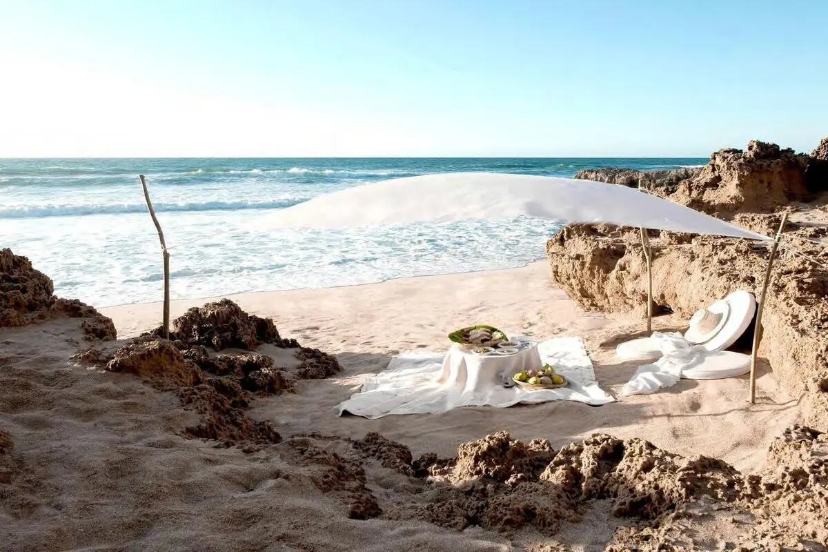 Private picnic set on a quiet Caribbean beach with a sail-cloth canopy
