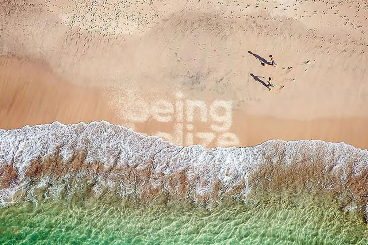 Aerial of two figures walking on a soft sand beach in Belize